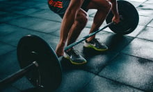 from legs down: person deadlifting against black mat