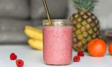 pink smoothie with fruit in the background
