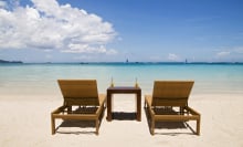 Two lounge chairs and table with drinks sitting on beach