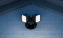Blink outdoor security camera affixed to home with two floodlights 