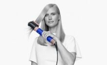 a person with long blonde hair uses the dyson airwrap hair dryer 