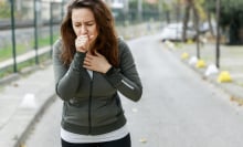 a woman coughing outdoors