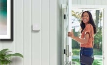 a woman leaves her front door while looking back into the house with an amazon smart thermostat attached the wall