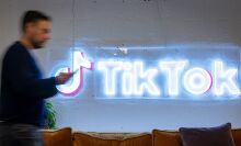 An employee looks at his mobile phone as he walks past the logo of the video-focused social networking service TikTok, at the TikTok UK offices, in London.