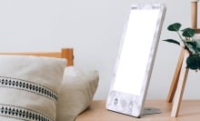 a verilux happylight luxe sits on a bedside table
