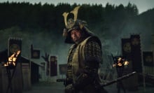 A man in samurai armor stands on a battlefield.