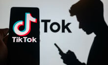 TikTok logo open on a phone screen next to the silhouette of a man looking at his phone. 
