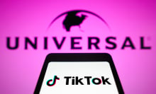 A phone displaying the TikTok logo in front of a pink sign reading "Universal."