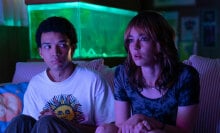 Two people sit on a sofa in the glow of the TV.