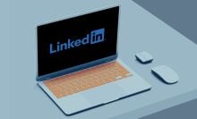 A mockup of the LinkedIn logo on a laptop sitting on a white desk.