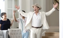 A man in a white suit throwing his hands up in excitement.