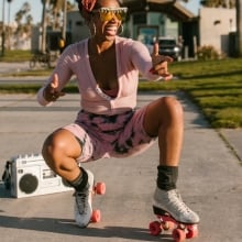 Black woman posing on roller skates with boombox behind them.