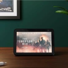 an amazon echo show sits on a tabletop showing a movie title screen