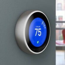 a google nest learning thermostat on a blue wall