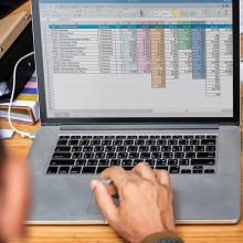 Someone typing on a computer with an open spreadsheet file