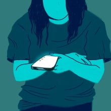 A woman looks down at her glowing phone.