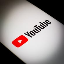 The YouTube logo is illuminated on a smartphone