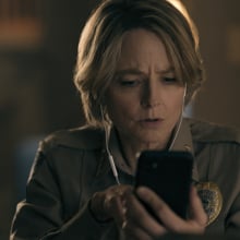 A woman in a police uniform watches something on her phone.