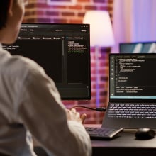 man coding on monitors