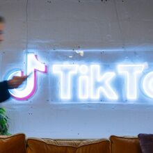 An employee looks at his mobile phone as he walks past the logo of the video-focused social networking service TikTok, at the TikTok UK offices, in London.