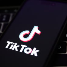 A laptop keyboard and TikTok logo displayed on a phone screen are seen in this illustration photo