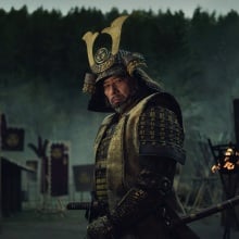 A man in samurai armor stands on a battlefield.