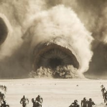 Three massive sandworms race toward an army of humans.