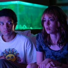 Two people sit on a sofa in the glow of the TV.