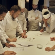 A group of chefs gather around a table.