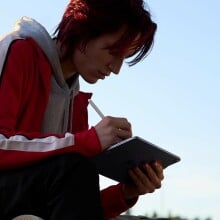 a person sits cross-legged outside while using an apple iPad air tablet with an apple pencil