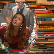 Máiréad Tyers looks through a hole in a wall of books in the TV series "Extraordinary."