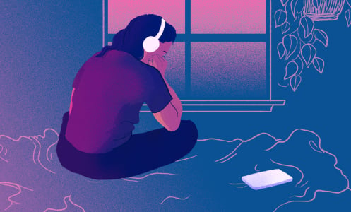 A young person listens to headphones on their bed.