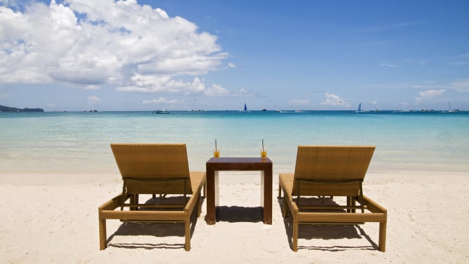 Two lounge chairs and table with drinks sitting on beach