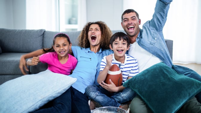 a family cheers while watching a football game from the couch