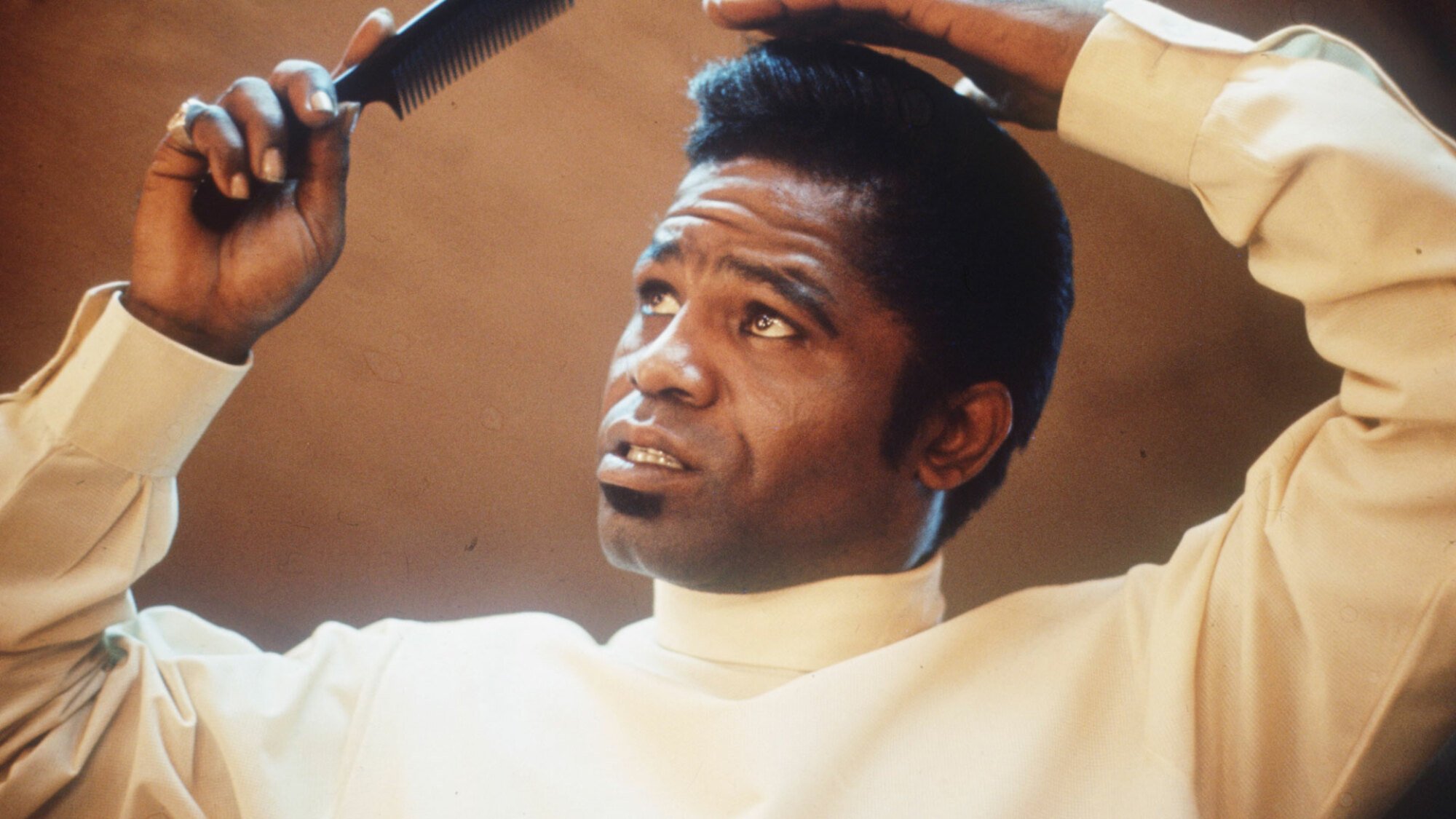 A young James Brown combs his hair.