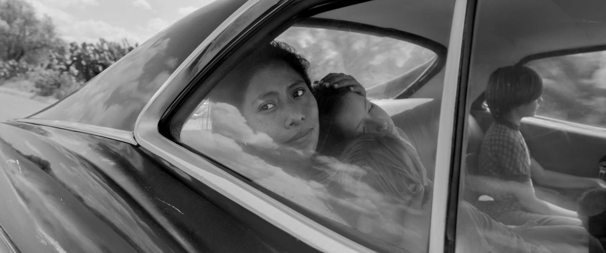 A woman and two children in the backseat of her car.