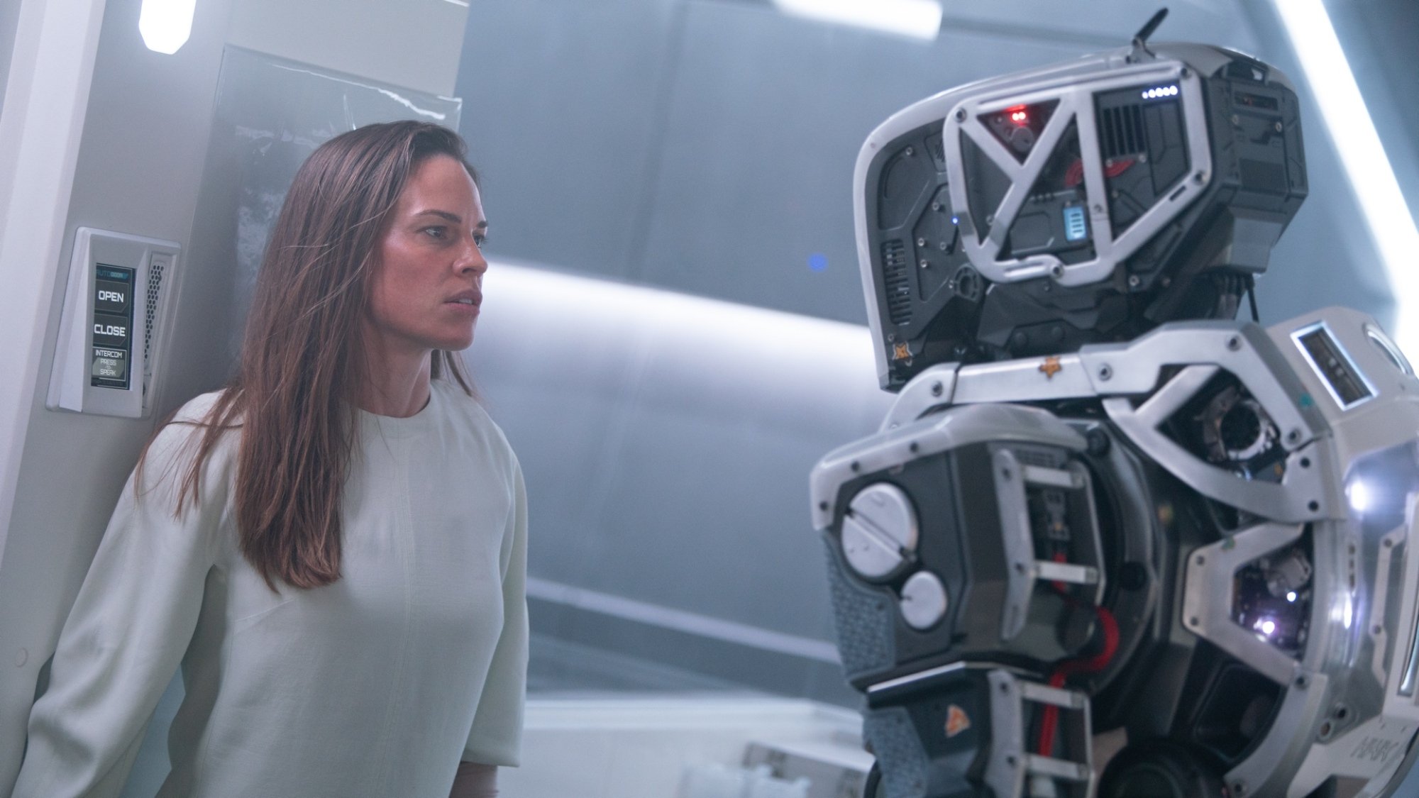 A woman faces off against a tall robot.