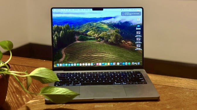 the 14-inch, m3 pro apple macbook pro on a wooden table next to a houseplant