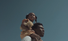 A father carries his daughter on his shoulders. 