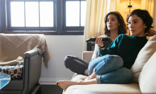 two women sitting on couch watching TV