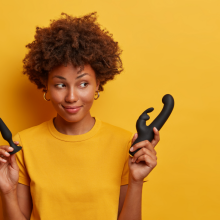 woman holding sex toys against yellow background