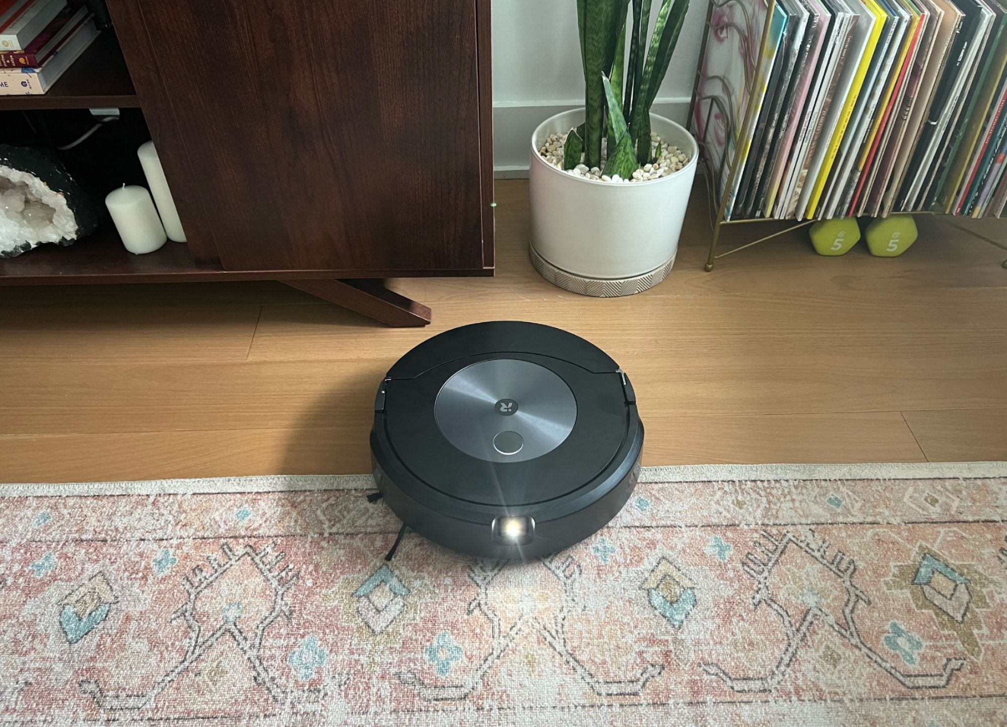 Roomba with LED light facing forward cleaning rug and hardwood floor