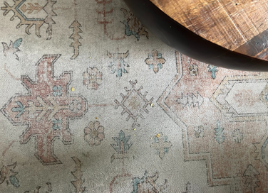 A few chip crumbs on patterned rug with round coffee table in corner
